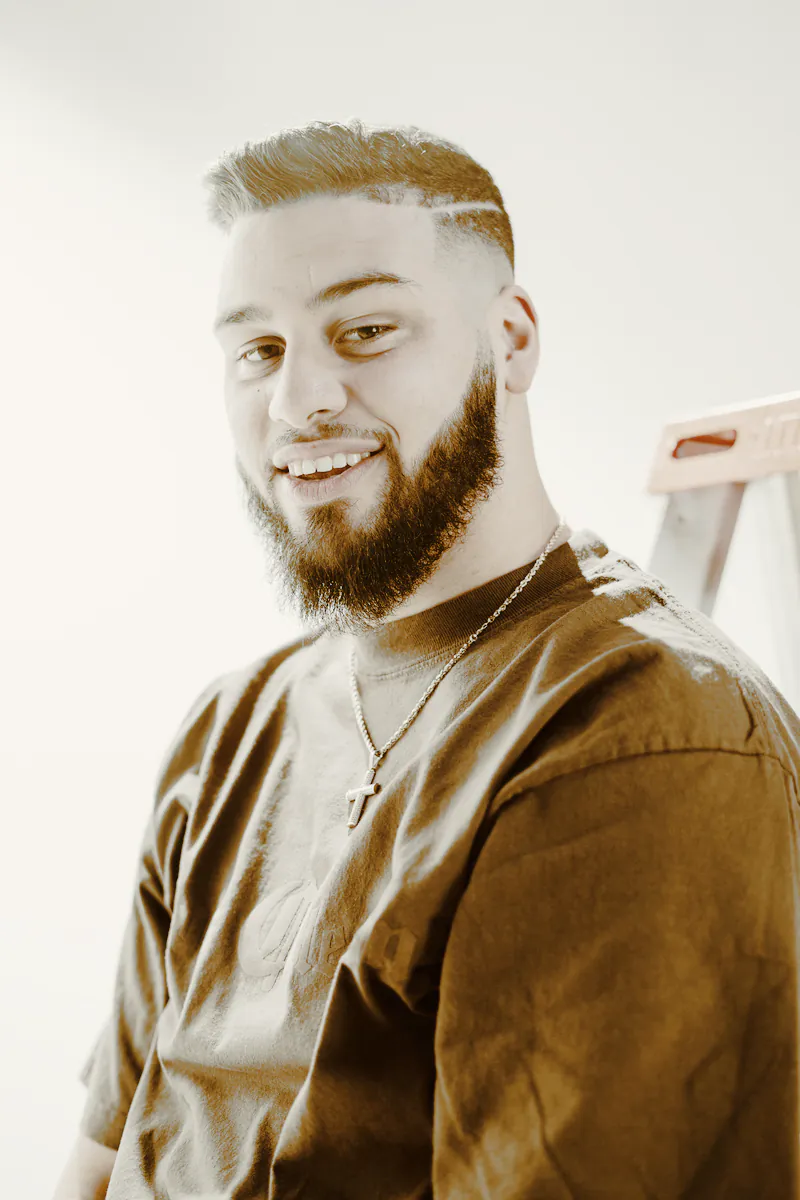 A smiling man with a fresh fade and a full, shaped beard