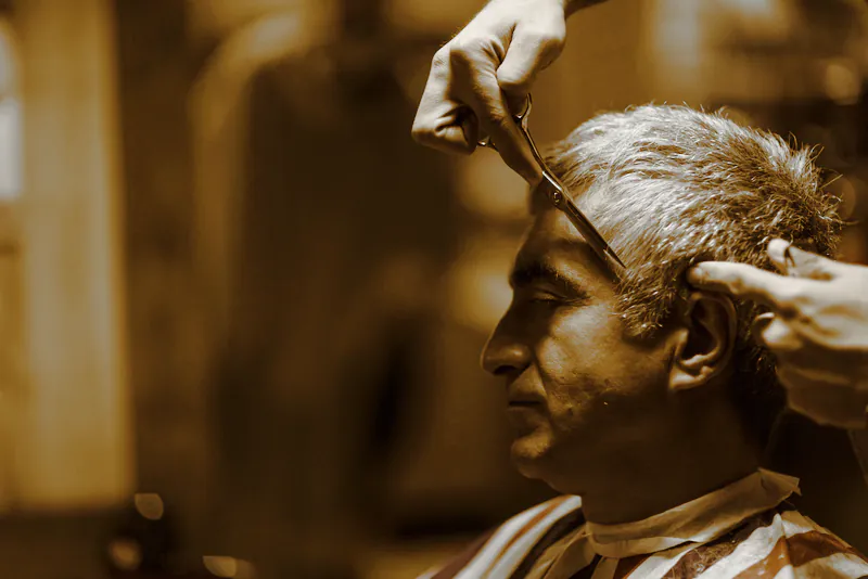 An older client with grey hair having it combed and cut