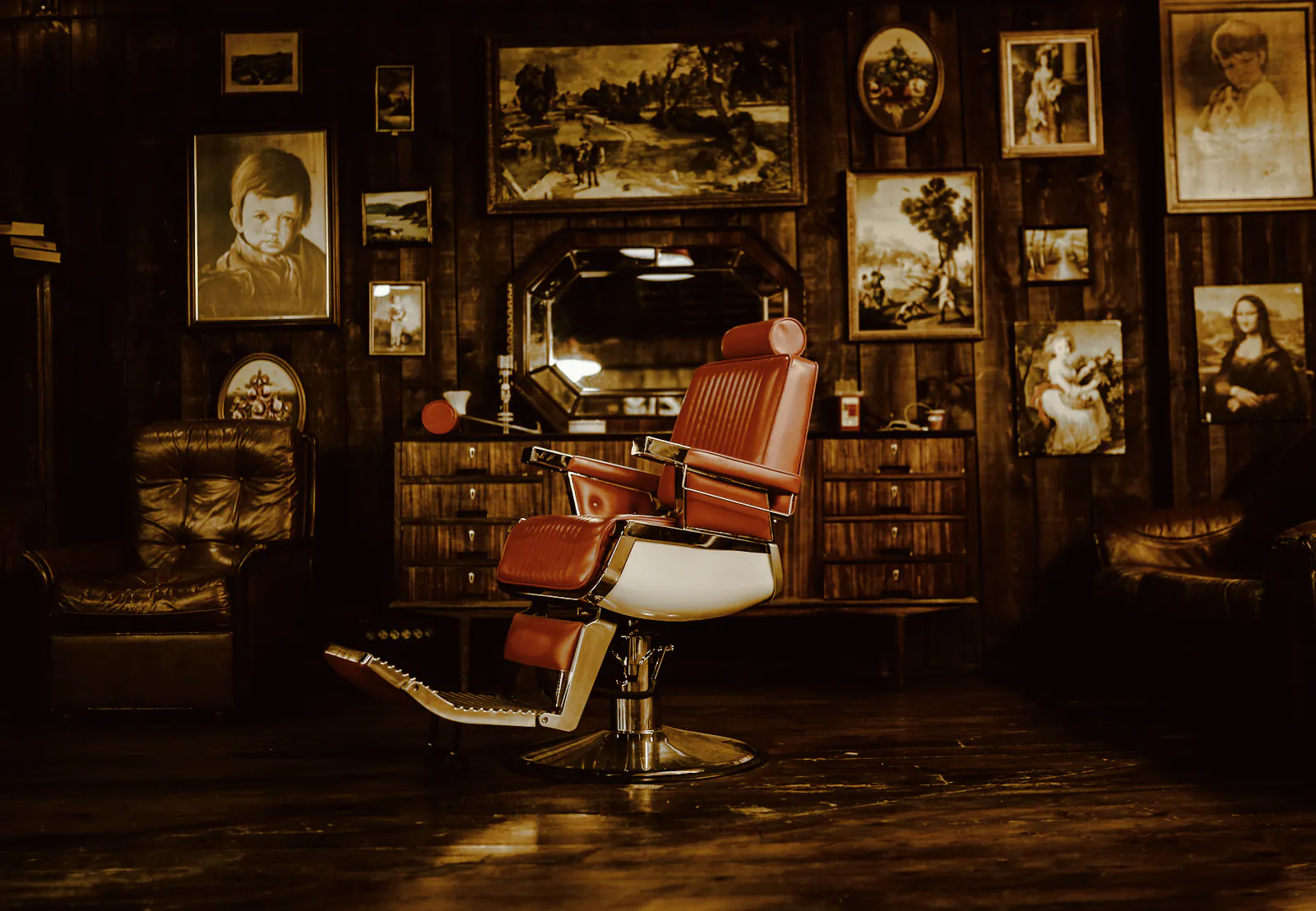 A red leather barber chair in a dim room hung with framed pictures
