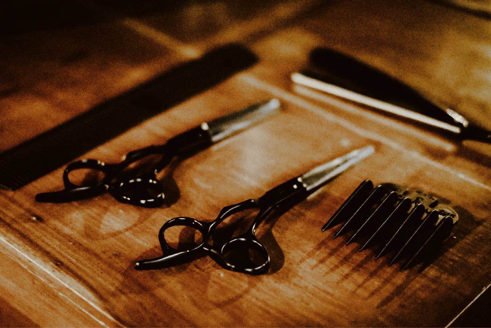 Barber scissors, combs and a razor laid out on a polished timber bench