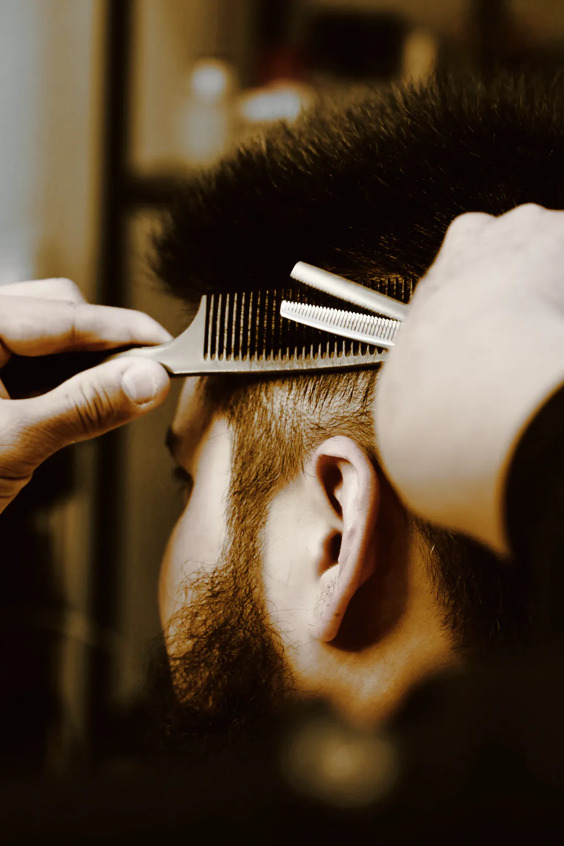 A barber thinning the top of a client’s hair with shears and a comb