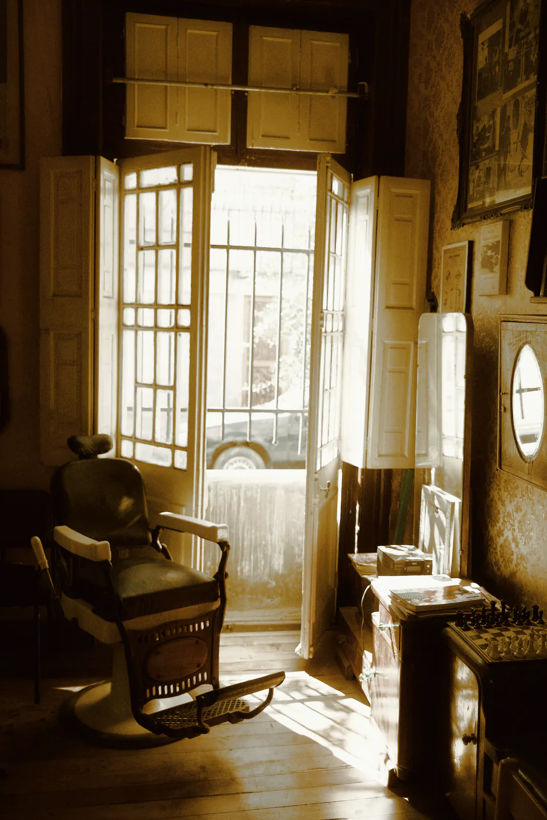 An old barber chair in a quiet room, lit by afternoon sun from an open doorway
