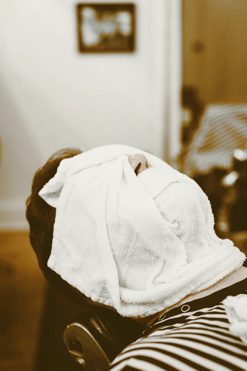 A client reclining with a hot towel wrapped over his face